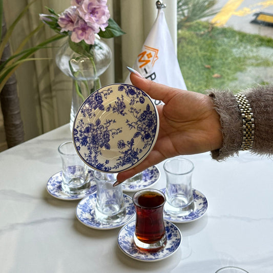 أكواب شاي زجاجية مع صحون مزخرفة بنقوش زهور زرقاء